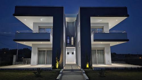 a large white building with two balconies at night at Pearl Luxury Suites in Paralia Dionysiou