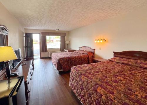 a hotel room with two beds and a television at Landmark Inn On The River Sevierville in Sevierville