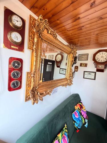 a mirror on a wall with clocks and a couch at Domek KALINKA -Góry Sowie-Rzeczka in Rzeczka