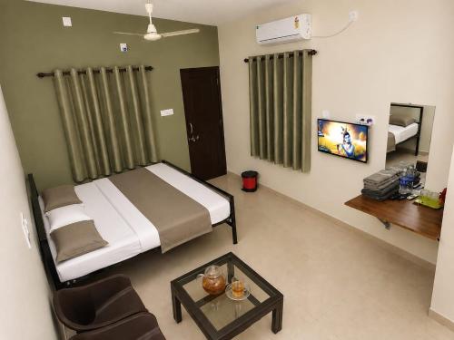 a bedroom with a bed and a table and a tv at Shyams homestay MV in Malpe