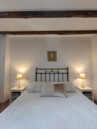 a bedroom with a bed with two lamps on two tables at La Simona Casa Rural in Perales del Puerto
