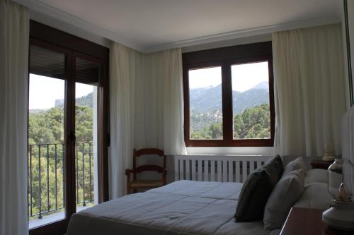 a bedroom with a bed and two large windows at La Posada del Conde in Ardales