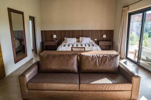 a living room with a couch in front of a bed at Atamisque Wine Lodge - Valle de Uco in San José