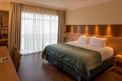 a hotel room with a bed and a large window at Bourbon Convention Hotel Santos in Santos