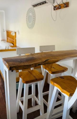 a wooden table with two stools next to a bedroom at Cabañas Portofino todo incluido in Ramallo