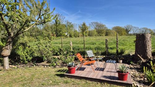 a wooden deck with a chair and some plants at Le Gite de François - Second Souffle - Urville in Urville-Nacqueville