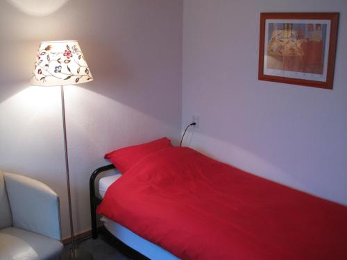 a bedroom with a red bed with a lamp and a chair at B&B Vincent's Attic in Ede