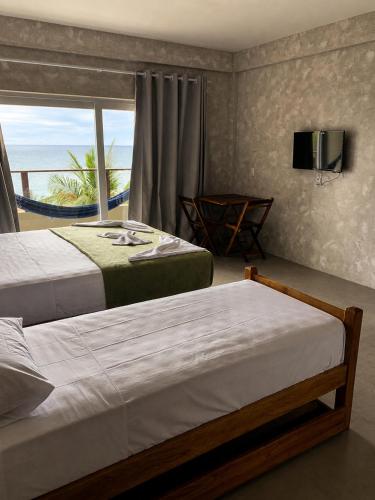a bedroom with two beds and a view of the ocean at Casas de Juan in Morro de São Paulo