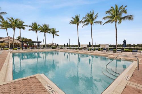 a large swimming pool with palm trees in the background at Kasa Wellington South Florida in Wellington