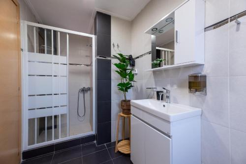 a white bathroom with a sink and a shower at DreamCoast Apartments I in Artemida