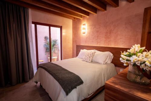 a bedroom with a bed and a vase of flowers at Hotel Casa de las Abuelas in Guanajuato