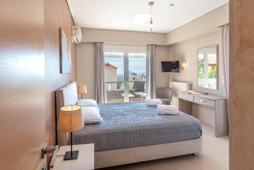 a bedroom with a bed and a desk and a window at DreamCoast Apartments I in Artemida