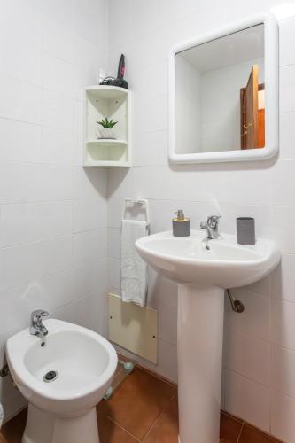 a white bathroom with a sink and a mirror at Refúgio do Mar -Steps from the Beach- in Armação de Pêra