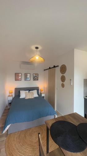 a bedroom with a blue bed and a table at Escapade paisible Studio design à Saint-Mesmin in Saint-Mesmin
