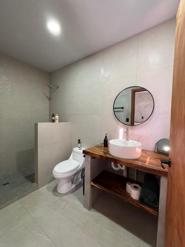 a bathroom with a sink and a toilet and a mirror at Shalpabay house - Private Apartments and Rooms in Taquillo