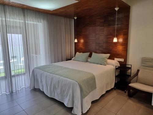 a bedroom with a large bed and a chair at Apartamentos El Arrecife in Conil de la Frontera