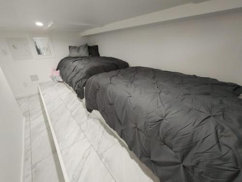 ein Schlafzimmer mit einem Bett mit grauer Bettdecke in der Unterkunft Quiet Ocean View Open Concept, Loft Style Studio within Forested Area, Near Parks & Ferry in Nanaimo