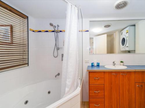 a bathroom with a shower and a tub and a sink at 2nd Floor 1-Bedroom Apartment in Urangan