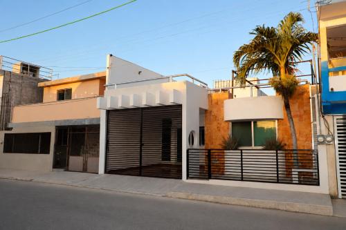 a white house with a gate and a palm tree at Casa con alberca en el centro de Puerto Progreso in Progreso