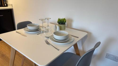 a white table with two plates and wine glasses on it at Central Old Town 1-Bed Apartment in Swindon