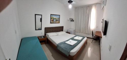 a small bedroom with a bed and a television at Solar da Praia in Vitória