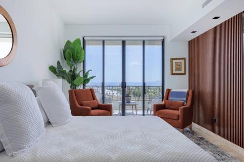 a bedroom with a bed and two chairs and a window at Modern 4BR Villa with Rooftop & Pickleball in Los Barriles