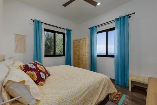 a bedroom with blue curtains and a bed with pillows at Pool with a View in Buena Vista in Buenavista
