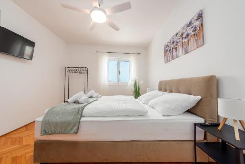 a bedroom with a bed with a ceiling fan at Laguna Rooms in Pag