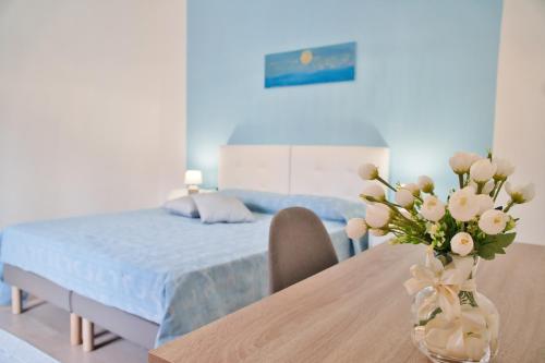 a bedroom with a bed and a table with a vase of flowers at ARCU DE CHELU - GUEST HOUSE in Modolo