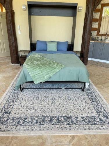 a bedroom with a bed with a blue bedspread and a rug at The Cross Patio Retreat in Buda