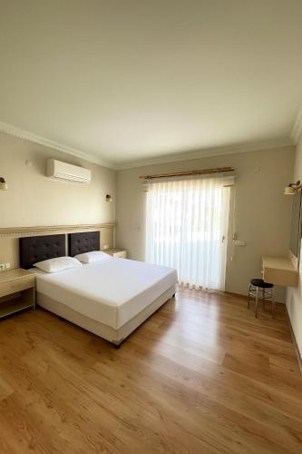 a bedroom with a large white bed and a wooden floor at Maison Edina - Cunda in Ayvalık