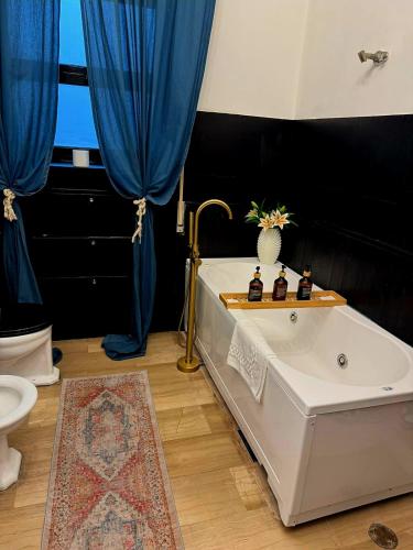 a bath tub in a bathroom with blue curtains at Visconti suite and spa in Catania