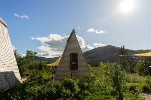 a small building with a pointed roof in a garden at Farouche Tremblant Cabines nature avec bain nordique in Lac-Superieur