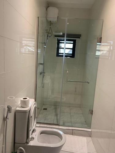 a bathroom with a toilet and a glass shower at Greyfield Apartment Anex in Benin City