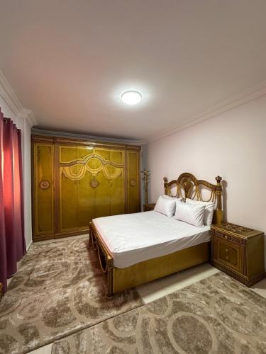 a bedroom with a bed with a wooden headboard at Spacious Apartment In 6 October in 6th Of October