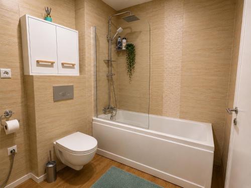 a bathroom with a toilet and a tub and a sink at Liberty Deluxe Apartment Cosmopolis in Creţuleasca
