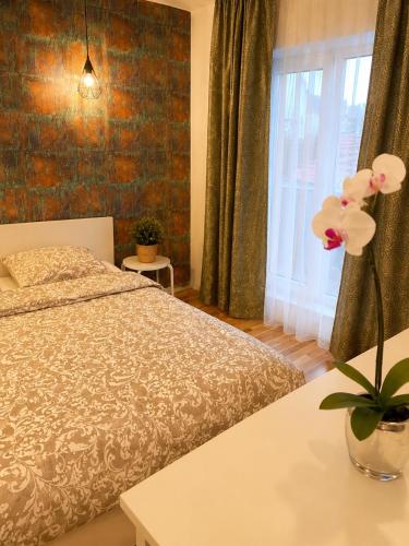 a bedroom with a bed and a vase with flowers on a table at Liberty Deluxe Apartment Cosmopolis in Creţuleasca