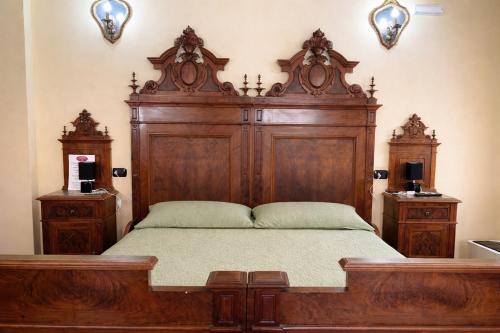 a large wooden bed in a bedroom with two night stands at B&B Il Fiocinino in Comacchio