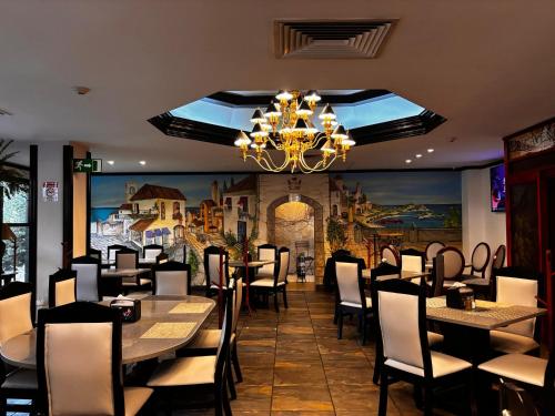 a dining room with tables and chairs and a chandelier at Taormina Hotel y Casino in San José
