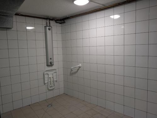 a bathroom with a white tiled wall and a urinal at Bateau Voilier Rochefort in Rochefort