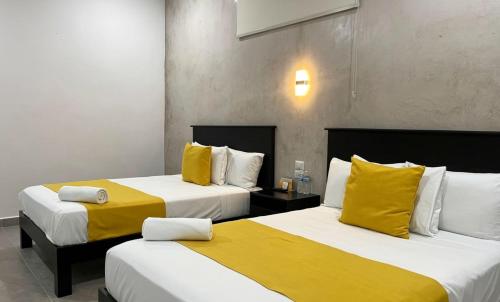 two beds in a hotel room with yellow pillows at Hotel Zibahun in Valladolid