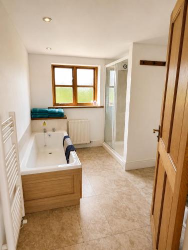 a large bathroom with a tub and a shower at Maesbury Riverside in Oswestry