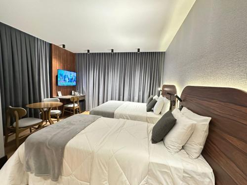 a hotel room with two beds and a table at Zallon Hotel Executivo - Late Checkout Cortesia as 15hs aos DOMINGOS in Lajeado