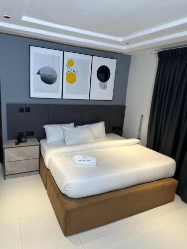 a bedroom with a large bed with pictures on the wall at Greyfield Apartment Anex in Benin City