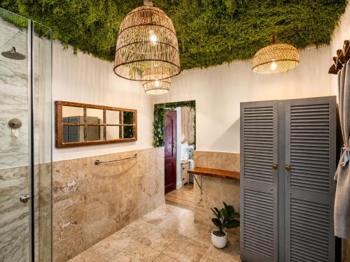 a bathroom with a walk in shower and two chandeliers at VistaBlu Camps Bay in Cape Town