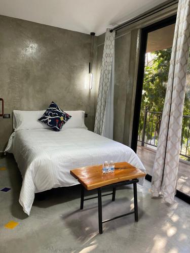 ein Schlafzimmer mit einem Bett, einem Tisch und einem Fenster in der Unterkunft Hotel Casa Grangelo in Atlixco