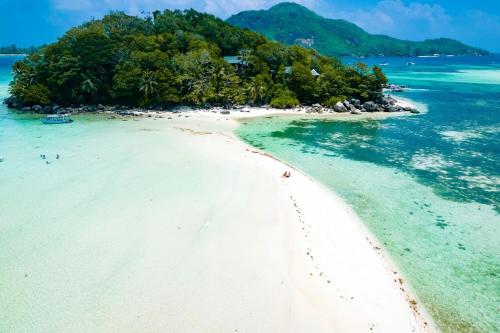 an island in the ocean with people on the beach at Enchanted Island Resort in Mahe