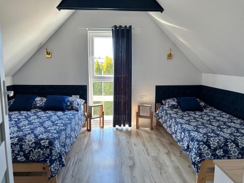 a attic bedroom with two beds and a window at Poprzeczna 7 in Sarbinowo