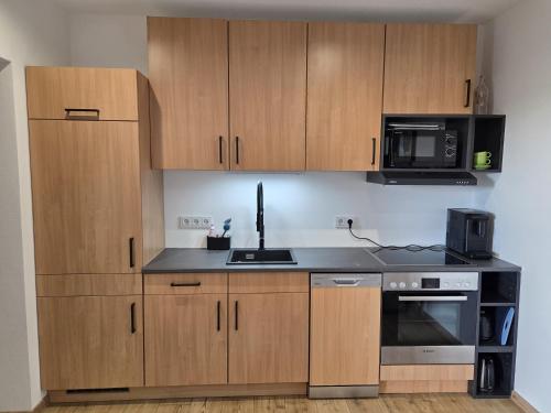 a kitchen with wooden cabinets and a sink and a microwave at RoSa Haus in Steingaden