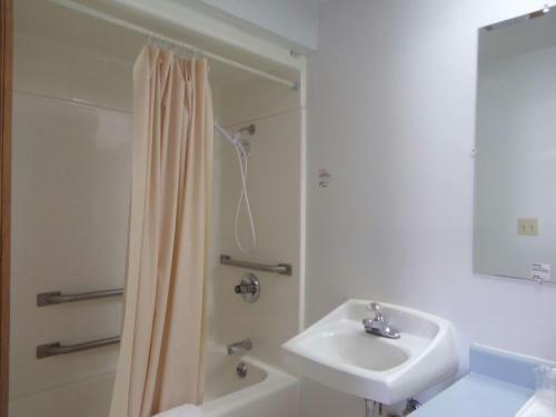 a white bathroom with a sink and a shower at Huggy Bear Motel - Warren in Warren